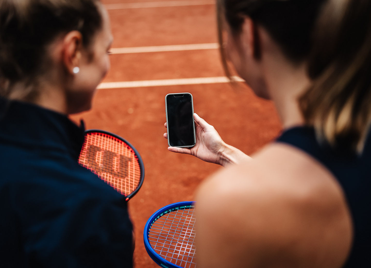 Zwei Tennisspielerinnen betrachten eine Smartphone