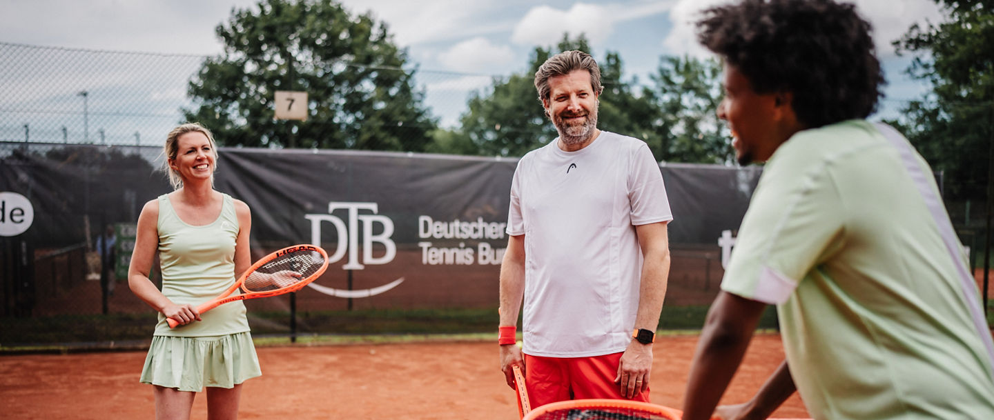Zwei Spieler:innen und ein Trainer auf dem Platz