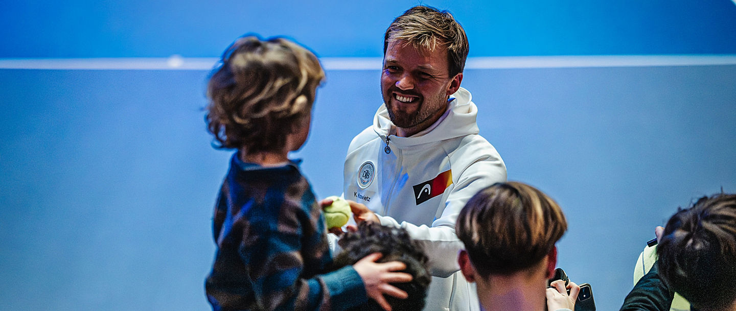 Kevin Krawietz schenkt kleinem Jungen beim Davis Cup in Düsseldorf einen Ball.