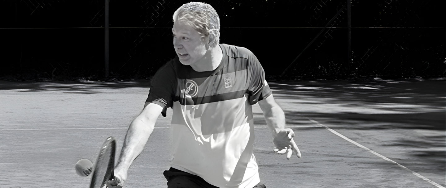 Man playing tennis on outdoor court in sunlight
