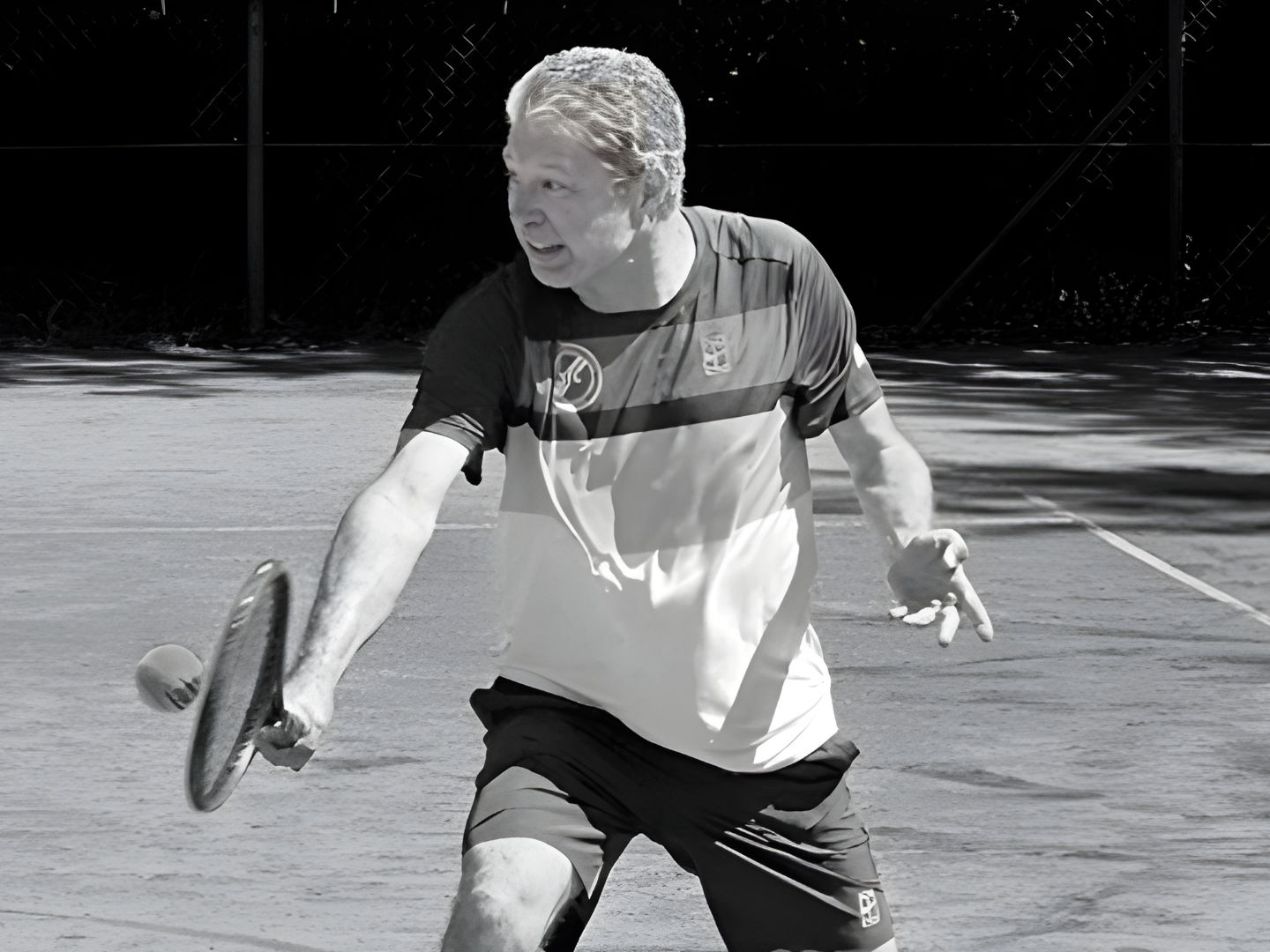Man playing tennis on outdoor court in sunlight