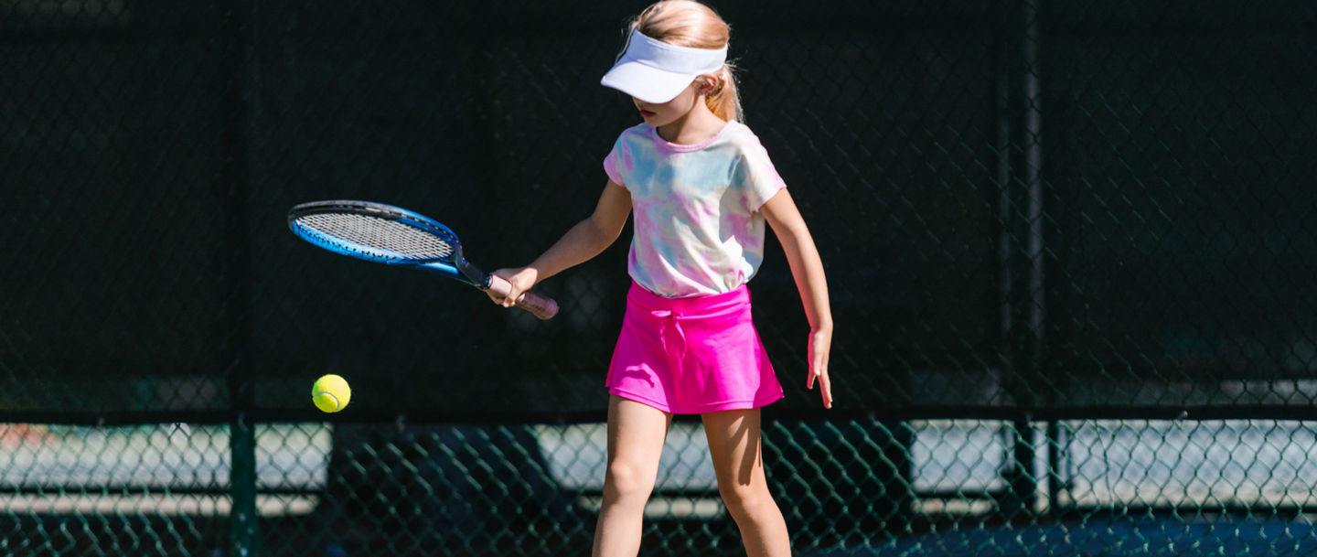Young girl playing tennis outdoors