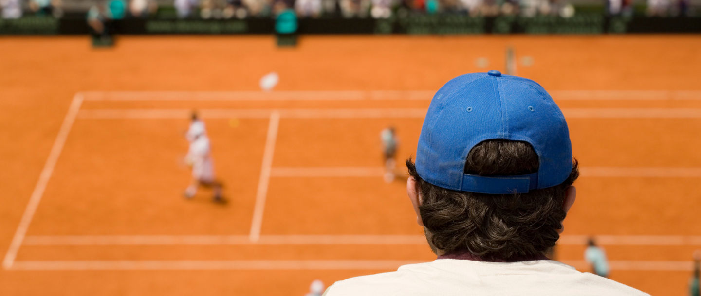 Spectator watching clay court tennis match