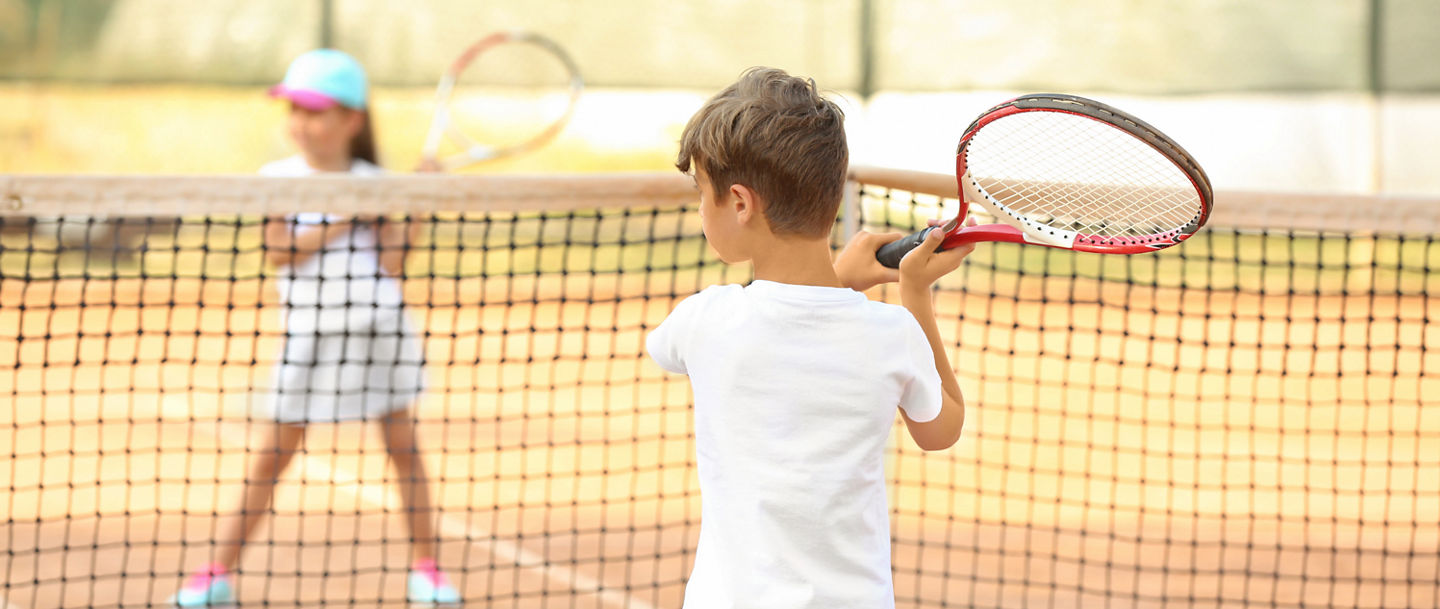 zwei Kinder spielen Tennis