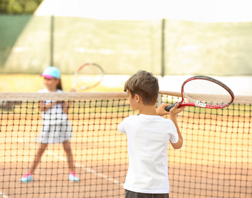 zwei Kinder spielen Tennis