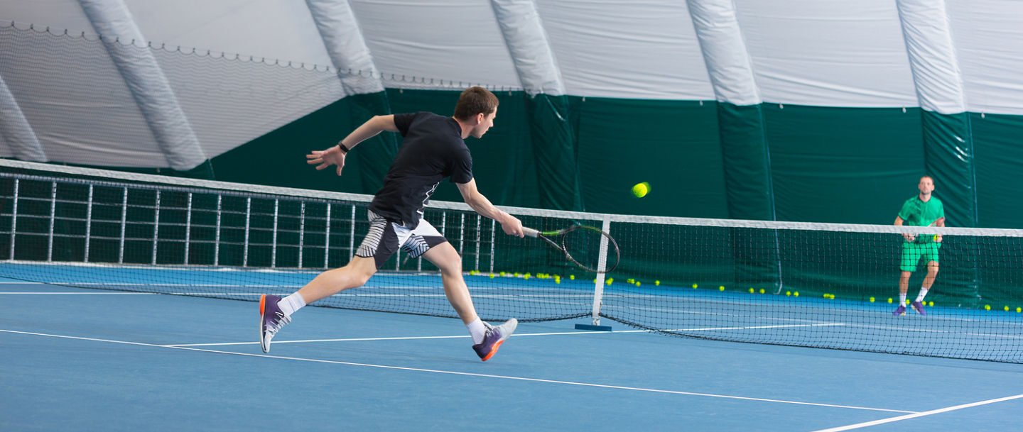 Hallenplatz mit zwei Tennisspielern gegeneinander