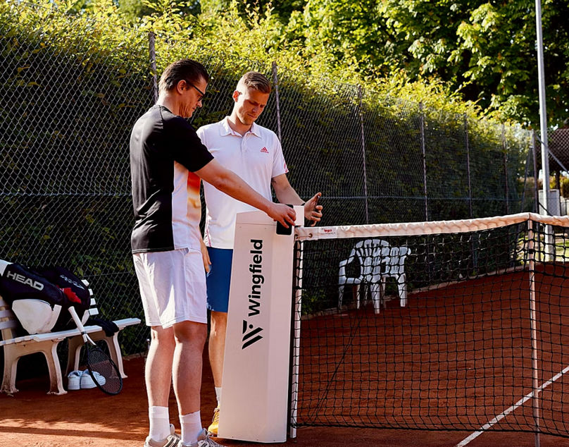 Tennis players discussing near Wingfield device